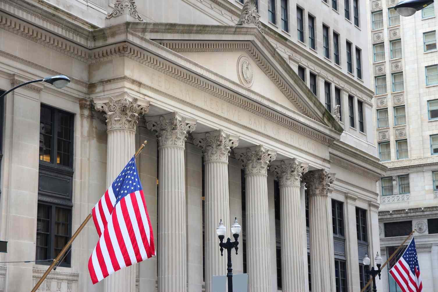 fachada do Federal Reserve, o Banco Central Americano, com duas bandeiras dos EUA