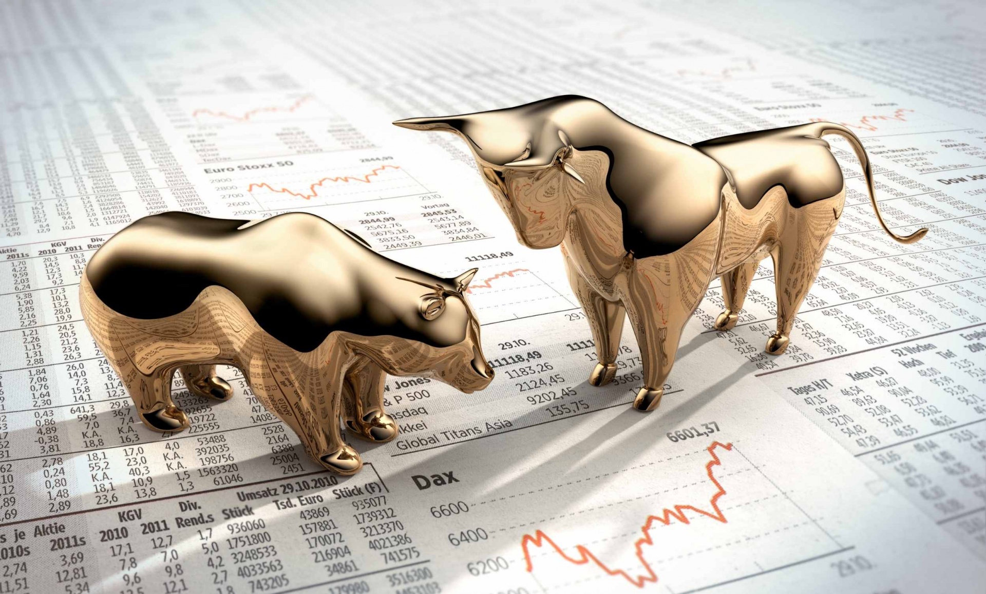 miniaturas douradas de um urso e de um touro estão frente a frente em posição de combate em cima de papéis com números e gráficos